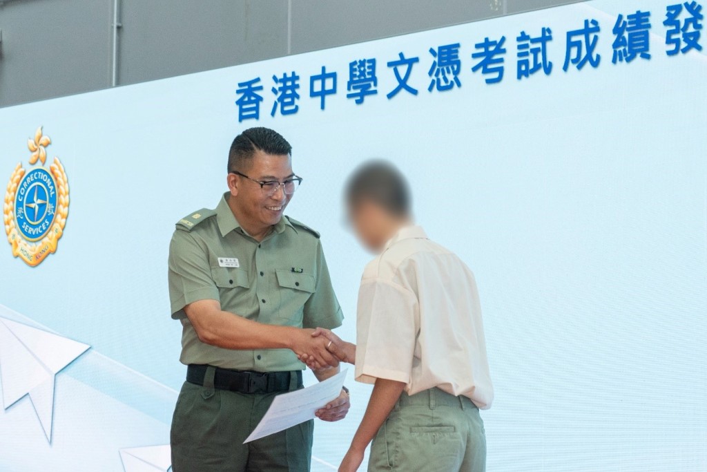 沙咀惩教所监督潘浩霖向其中一名考生颁发成绩通知书。