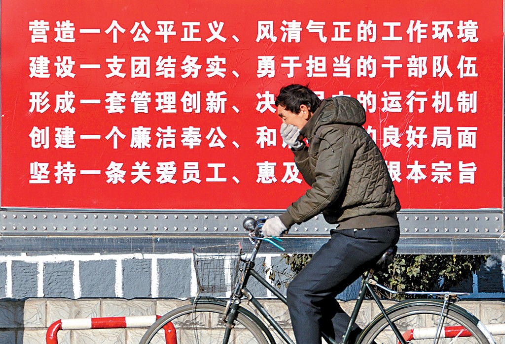山西大同街头，民众经过反腐宣传栏。