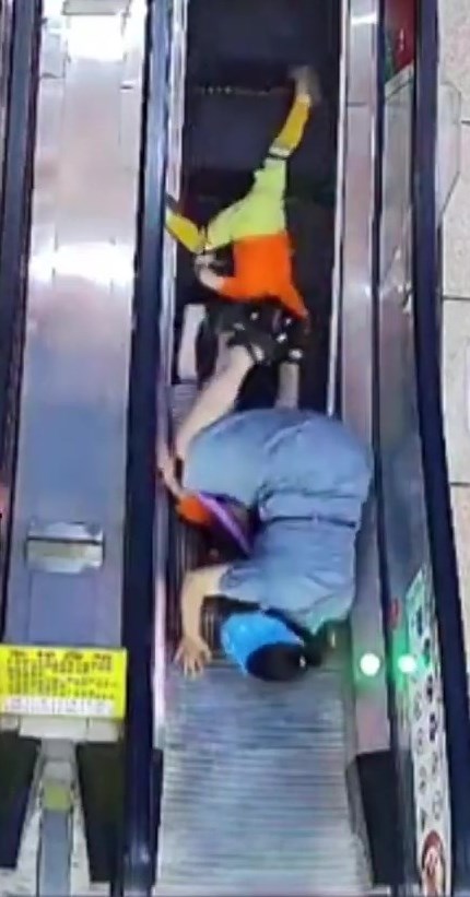 3人在狹窄的扶手電梯上一仆一碌如滾地葫蘆。網上截圖