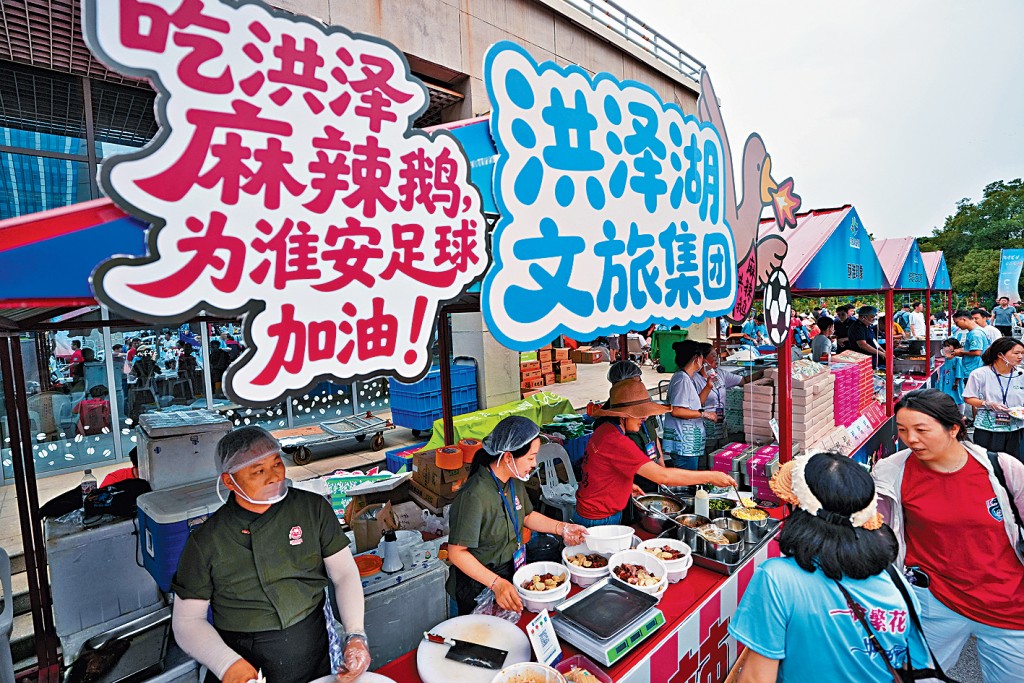 球迷在江蘇淮安「蘇超」市集選購各類美食特產。