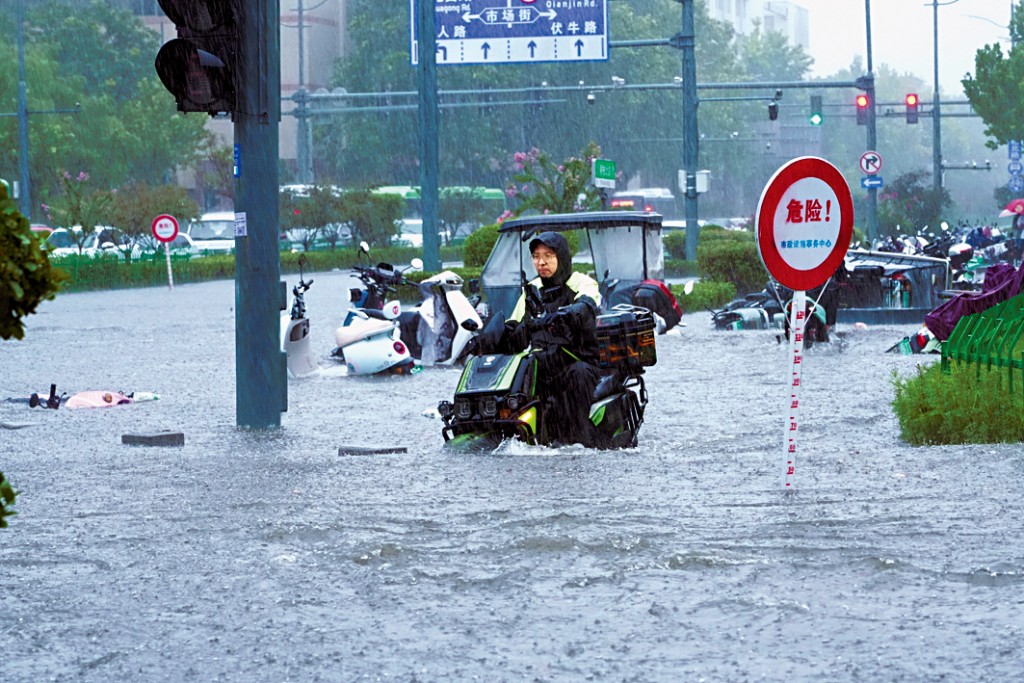 鄭州市民在暴雨中騎車出行。