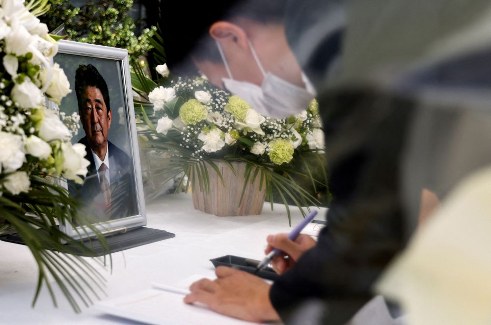 日本東京自民黨總部的祭壇上，一位哀悼者在已故日本前首相安倍晉三的照片前簽名。路透社圖片