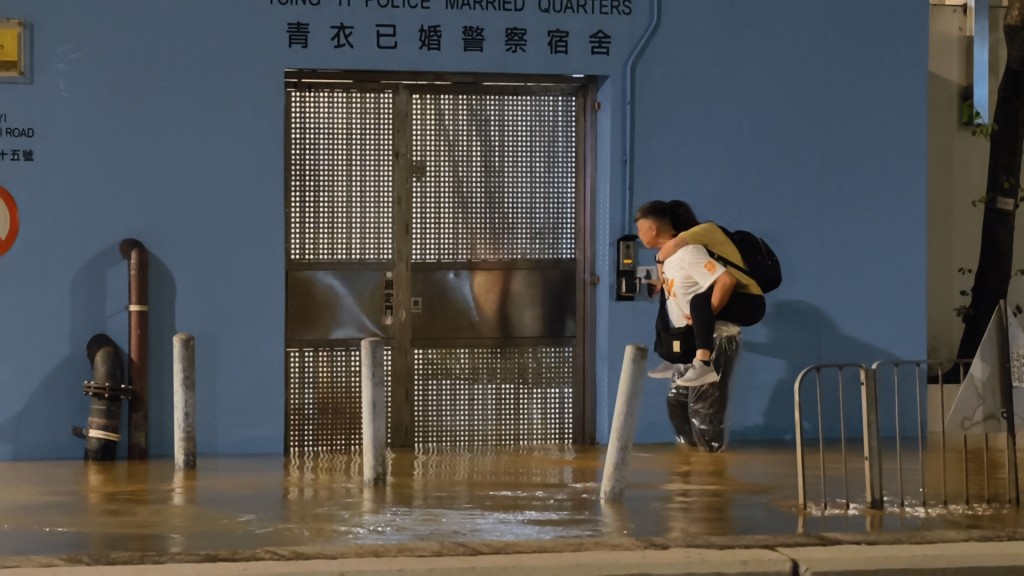 有男子背著女子涉水而行。黃文威攝