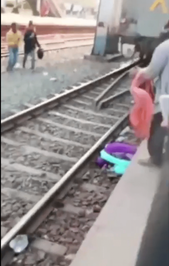 列车驶离后，见到妇女仍跪趴在路上边绿，而其身下正护着两名孩子。