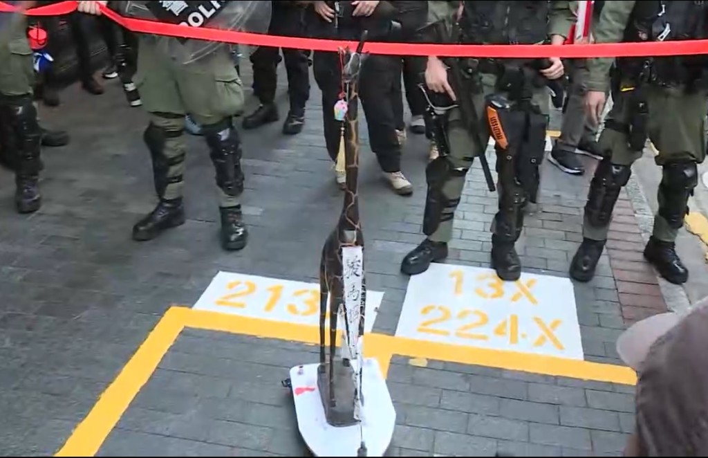 男子帶同一個長頸鹿雕像到警方封鎖綫前。無綫截圖