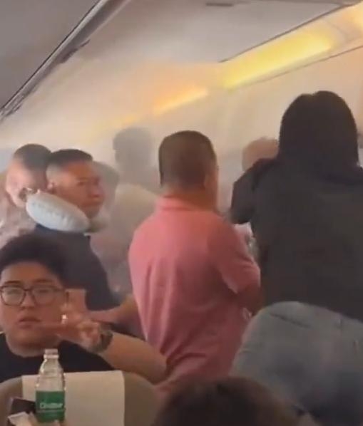 機艙內濃煙密布,乘客慌忙協助救火。 機艙內濃煙密布,乘客慌忙協助救火。