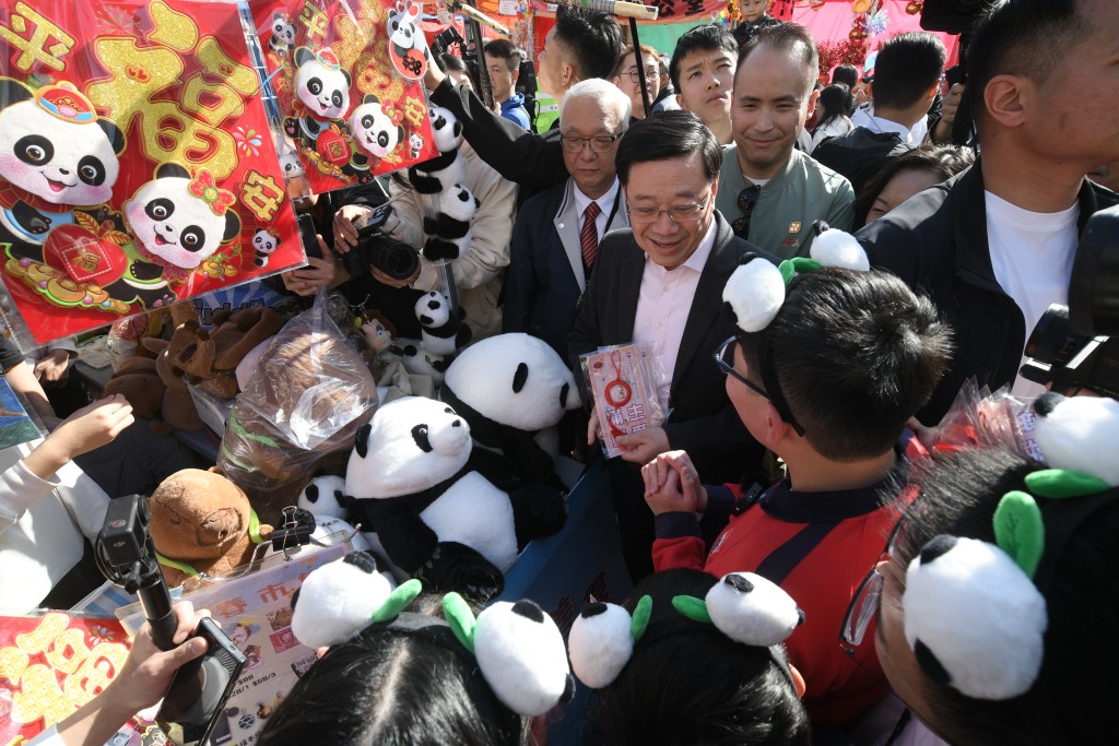 李家超與小學生交談，買下熊貓主題福字揮春掛物。（陳浩元攝）