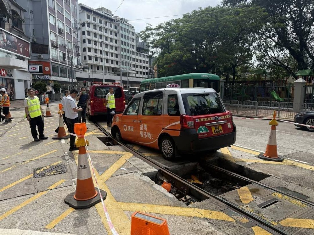 一轉的士衝入維修中的電車路軌，其前轆陷入坑內被困。網上圖片