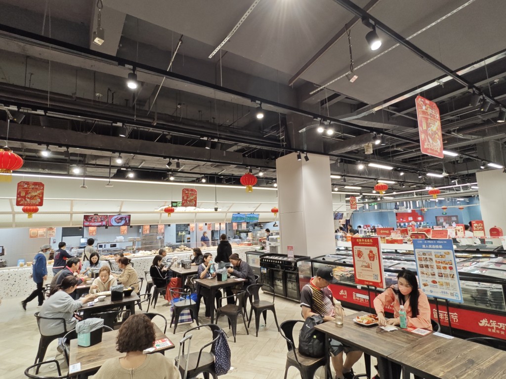 超市设有熟食空间及餐桌，让顾客大快朵颐。