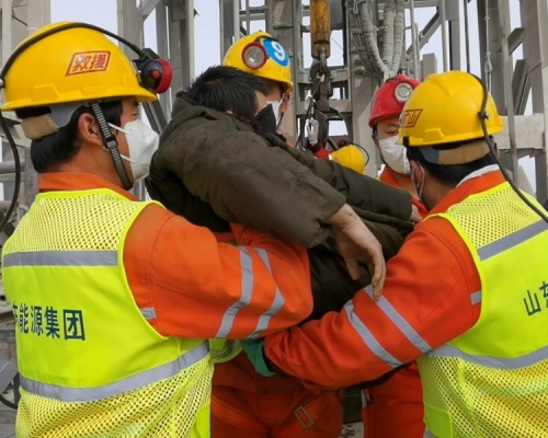 首名获救矿工双眼蒙上黑布送院。新华社