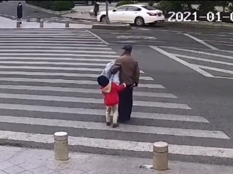 孫女在馬路中央嘗試拉住爺爺的衣服阻止。影片截圖