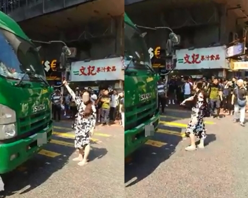 一名操內地口音的婦人緊握着貨車的前鏡，阻擋貨車前行，並不停着圍觀者「叫咗差佬先講啦」。影片截圖
