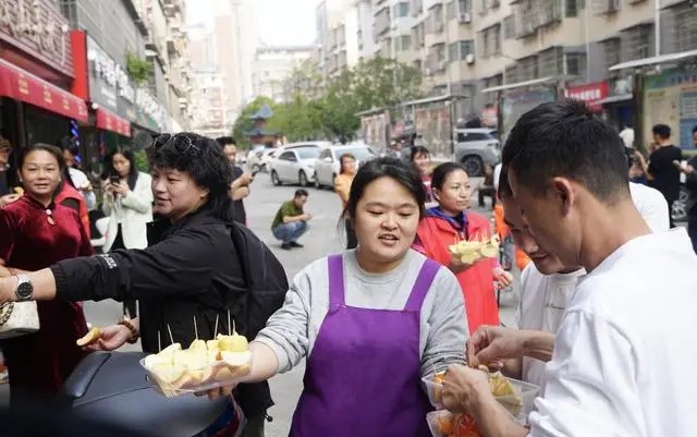 李晓华向店外的客人送上水果。