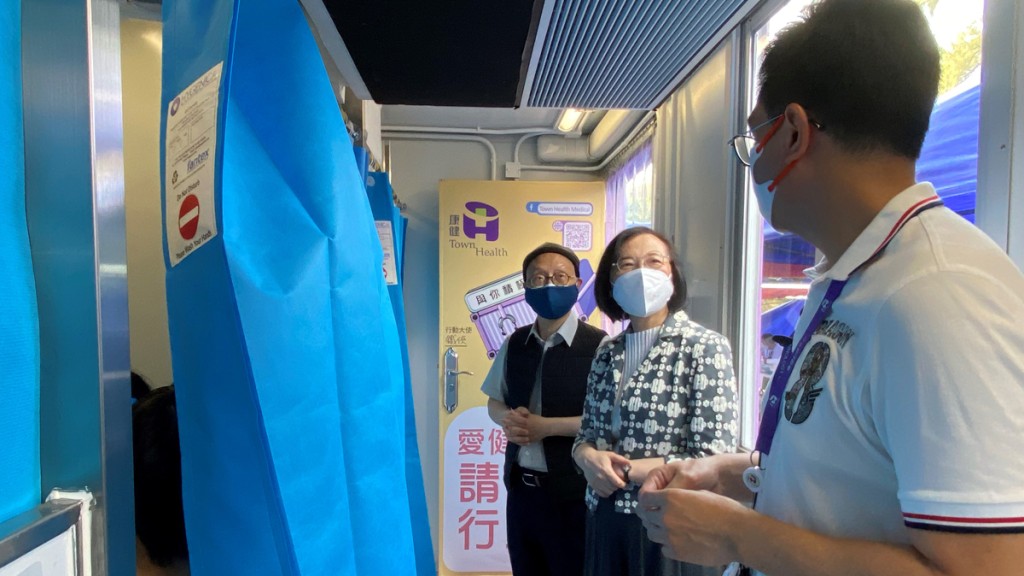陳肇始（中）聽取承辦商介紹該流動接種站的設施及運作。政府提供