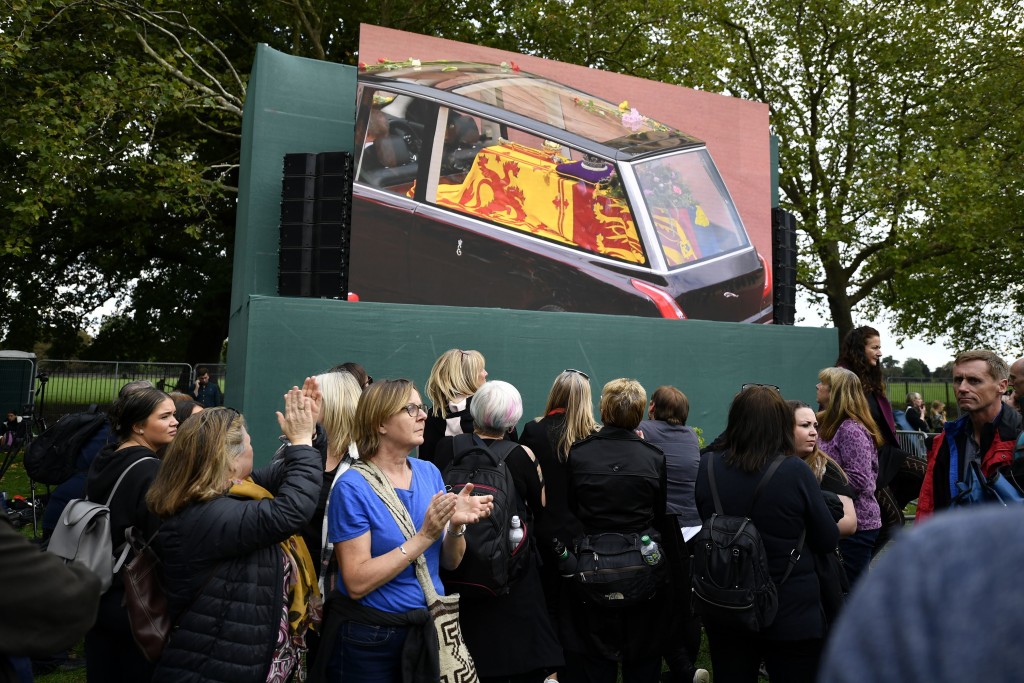 民众在大屏幕上观看英女皇伊利莎白二世的灵柩被送往温莎堡。AP