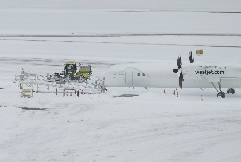 一名工人正在清理溫哥華國際機場西捷航空附近停機坪上的積雪。AP