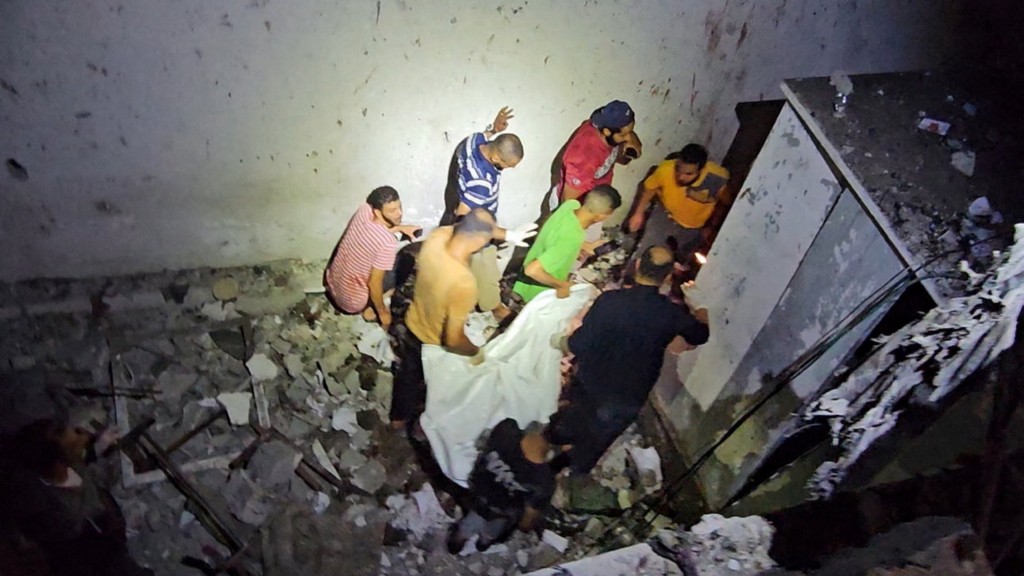 巴勒斯坦民众从以军空袭击中的UNRWA学校抬走尸体。 路透社