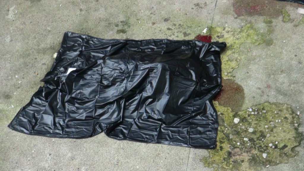 死者遺體由垃圾膠袋覆蓋。
