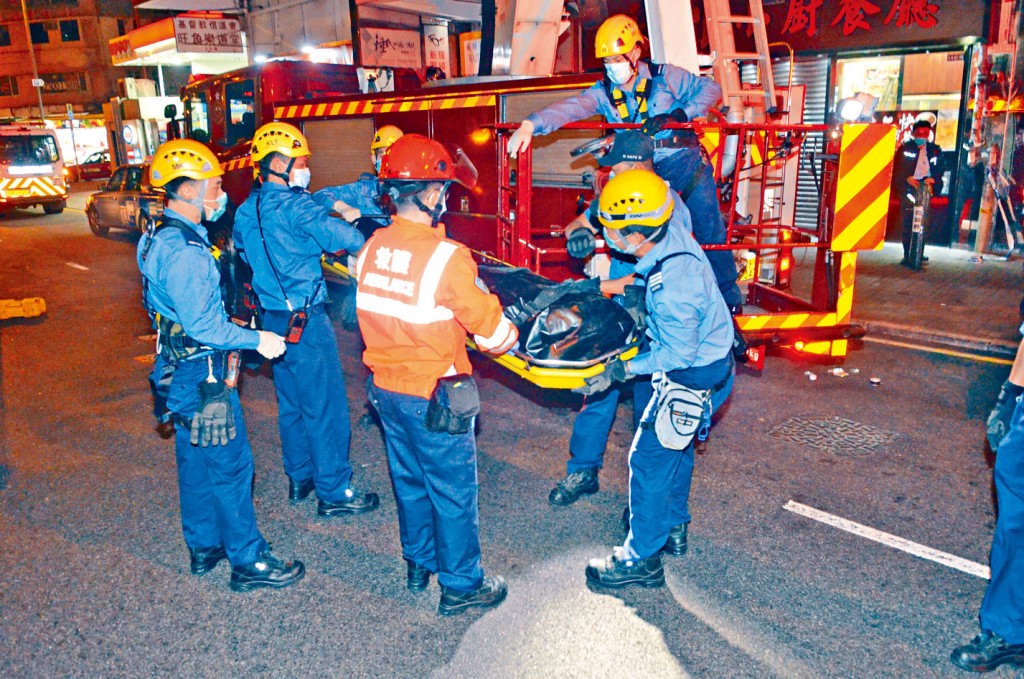 疑兇殺妻後在附近大廈跳樓身亡,消防員將遺體抬下。