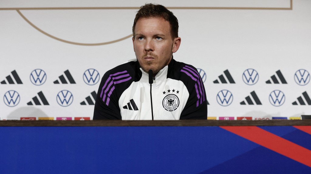 德国队教练在里昂见传媒，身后背景板和球衣都印有Adidas标志。 路透社