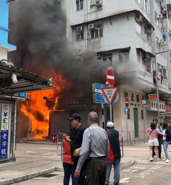 有地產舖女職員（粉紅衣）見火警欲奔返舖頭，遭警員阻止。