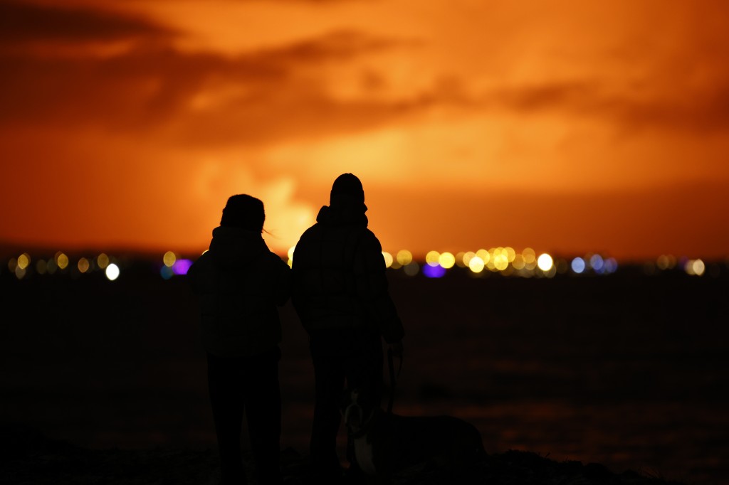 民众驻足观看冰岛橙红色夜空。美联社