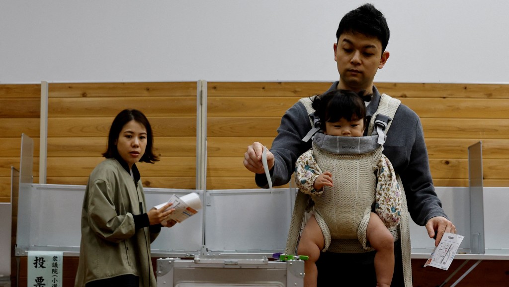 日本選民帶着嬰兒去票站投票。 路透社