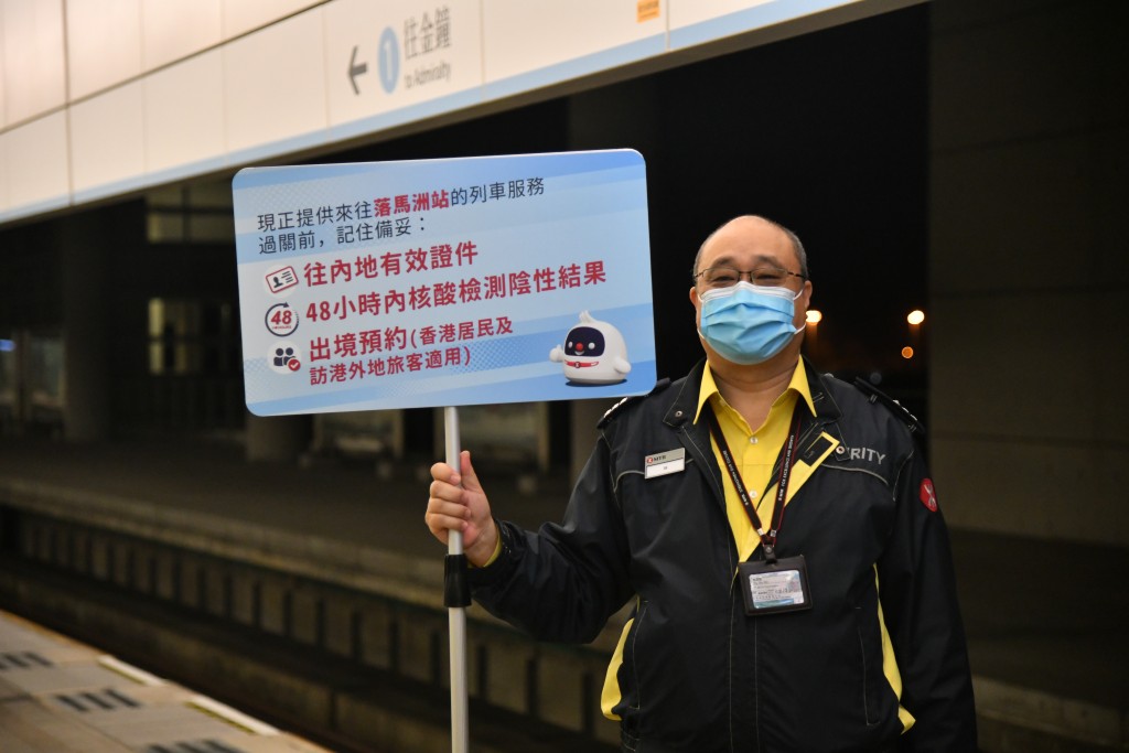 在落马洲站，有港铁职员举牌提醒市民过关所需文件。（卢江球摄）
