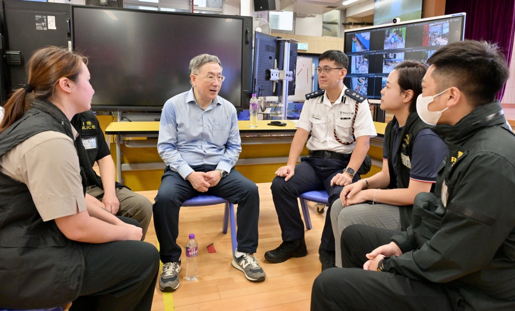 卓永興（左二）向大埔警區重案組組員了解如何處理上樓居民的求警協助個案。