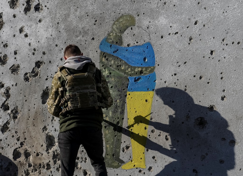 一名乌克兰艺术家在库皮安斯克在满是子弹和弹片痕迹的墙上涂鸦。路透