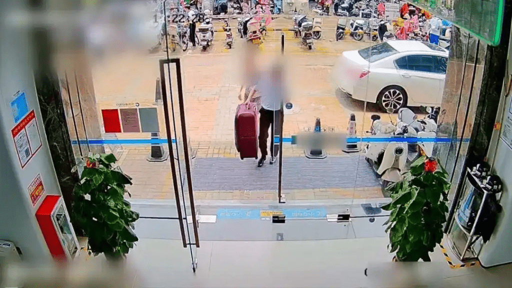 工作人員協助林女士(化名)將行李箱拿進銀行。 工作人員協助林女士(化名)將行李箱拿進銀行。