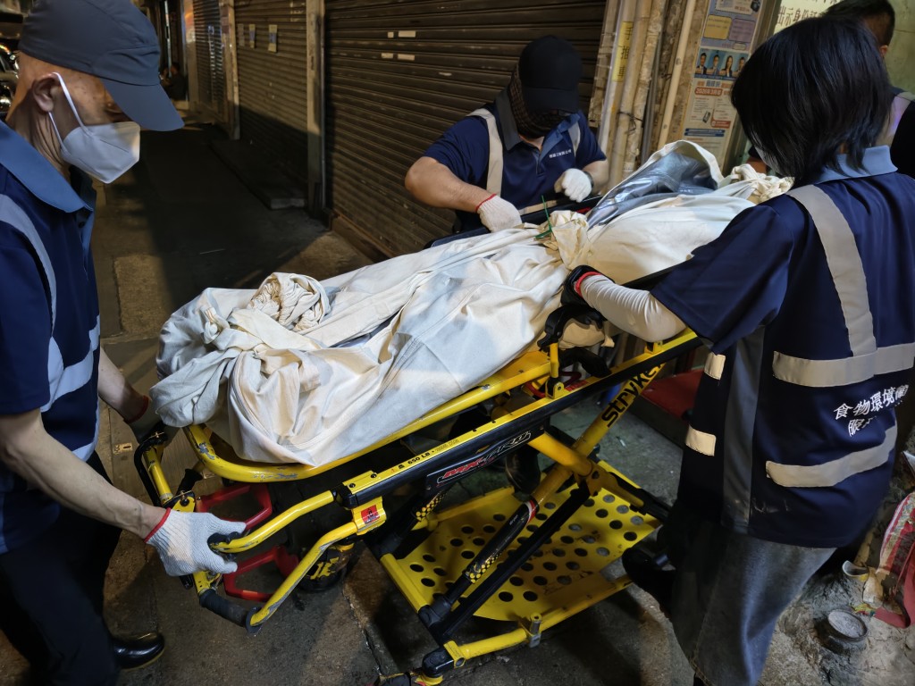 仵工將男死者的遺體搬落樓。