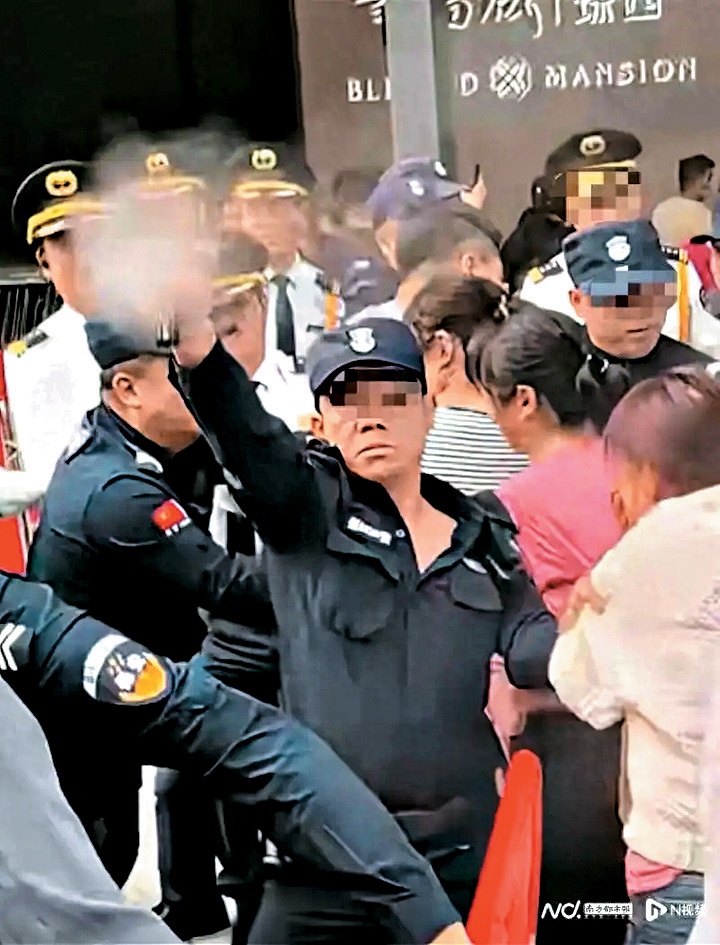 一位身穿保安制服的工作人員向人群噴灑噴霧。