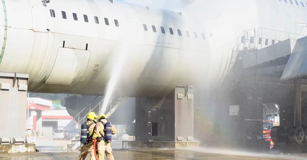 人员向飞机射水灌救。影片截图
