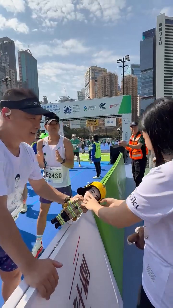 有人衝線時，高舉掛有何偉豪單人照片消防員公仔，之後緩緩跑向Kiki身邊。