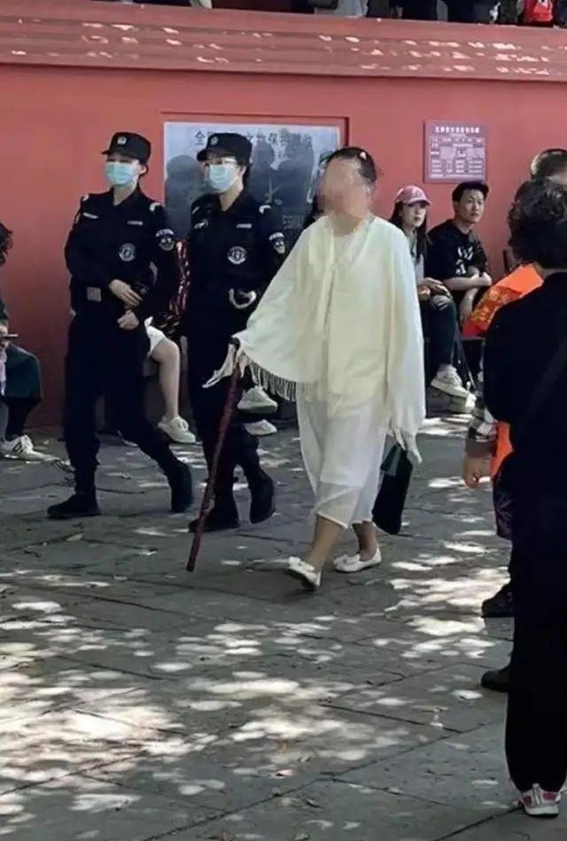白衣打坐女子被警方带走。