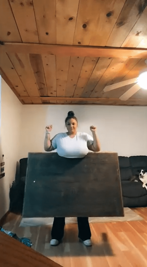 國外女子凱尤娜發起挑戰，用驚人巨乳夾住12公斤重的木桌。（截圖自TikTok）