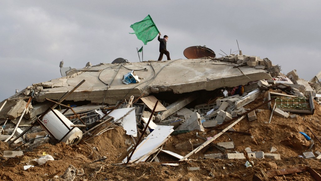 在2009年的以巴衝突中，巴勒斯坦男孩在加沙北部一處被炸毀的房屋上舉起哈馬斯旗。 美聯社