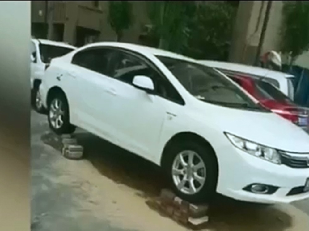 當地不少民眾為防座駕被洪水淹沒,自行以磚墊高汽車。影片截圖