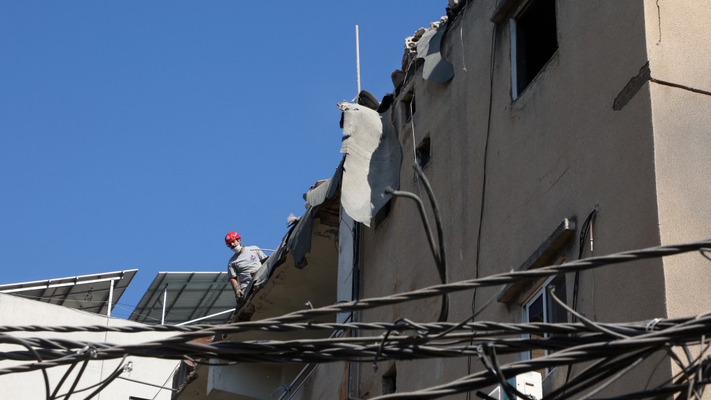 以色列空襲貝魯特南郊，真主黨屬下的民防隊成員視察受損建築。 路透社