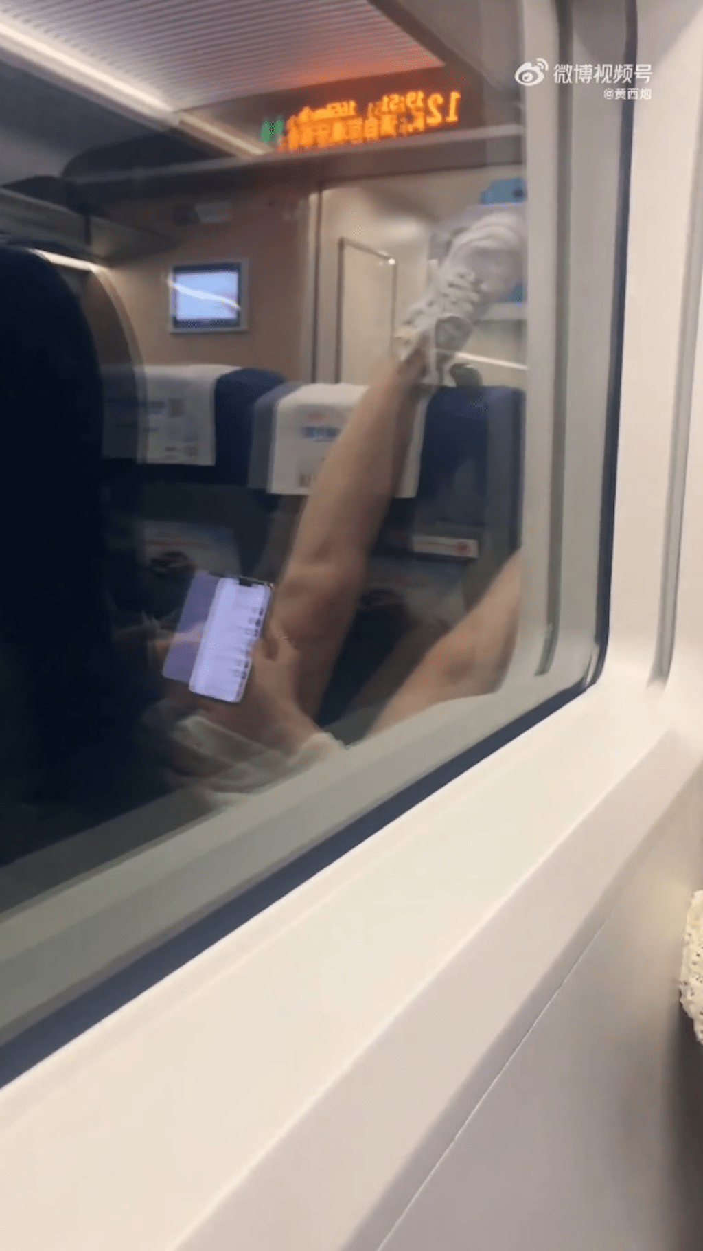 女子将腿高高翘起，放在前排乘客头上，一边还在看手机。