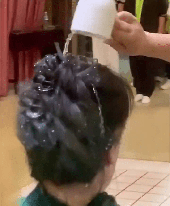 网传影片显示，一名女子头上被人淋了一杯水。