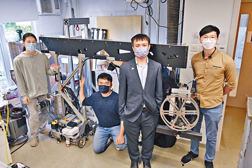刘达铭（右二）和团队研发的机械人系统，可代替建筑工人检测大厦外墙，有助减低工业意外风险。