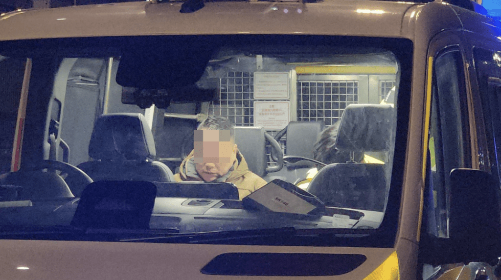 黑色七人車男司機坐在警車上。黎志偉攝