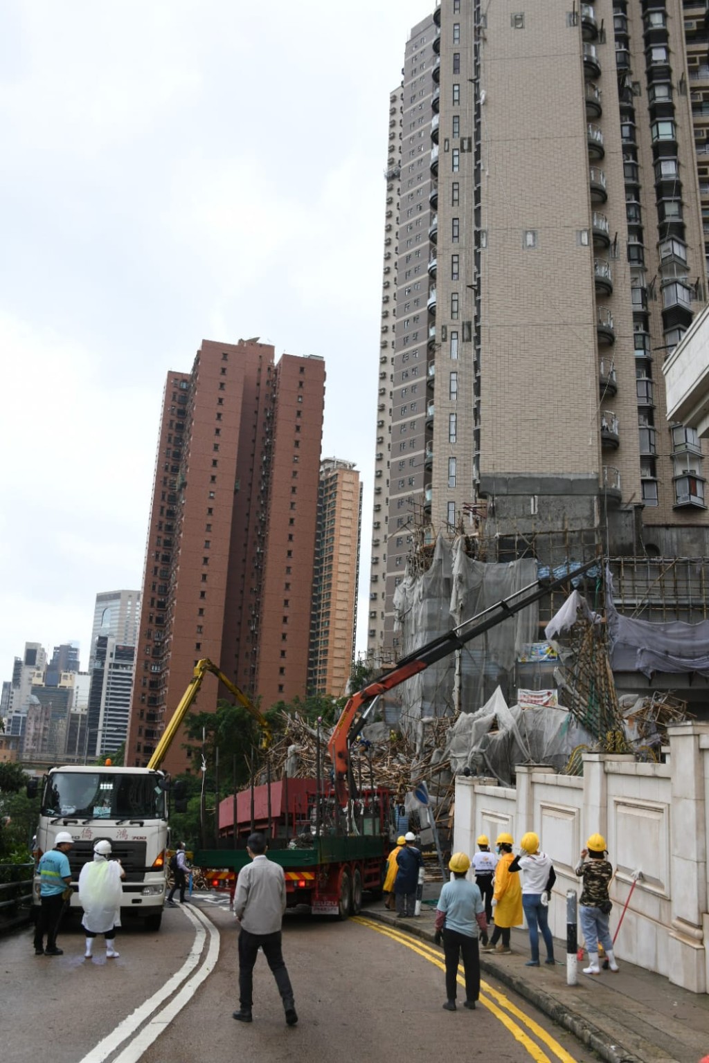 工人用吊臂車協助移走塌下的棚架。楊偉亨攝