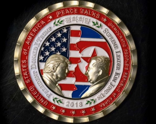 紀念幣上印有特朗普與北韓領導人金正恩面對面的金色浮雕,背景是拼接的兩國國旗。
