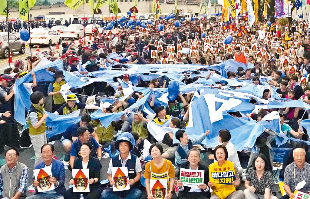 南韓示威者周六在首爾撕毀一面象徵國際原子能機構(IAEA)的旗幟,反對IAEA日前發表的福島核污水排海評估報告。