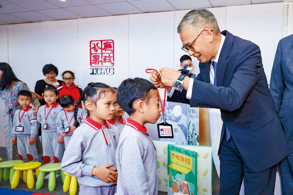 廉政專員胡英明(右)向學生派發特製的廉政主任證件。