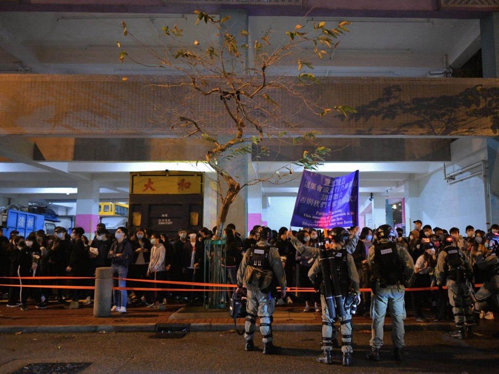防暴警察驅趕聚集人群上行人路,並拉橙色封鎖線,舉起藍旗。