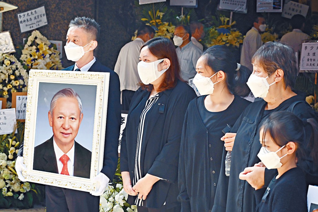 李少光兒子李霖恩捧着父親遺照步出靈堂。